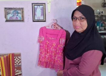 SURAYA Ahmad menunjukkan pakaian dan gambar Sharlinie Mohd. Nashar yang digantung di rumahnya di Kampung Padang Pulut, Dungun, Terengganu. - UTUSAN/NIK NUR IZZATUL HAZWANI NIK ADNAN