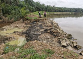 PENDUDUK meninjau kawasan ban sungai yang pecah tapi belum diperbaiki setelah air sungai surut di Kampung Kampung Permatang Pelandok di Pasir Salak. – UTUSAN/AIN SAFRE BIDIN