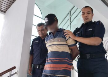 TERTUDUH diiringi anggota polis ketika dihadapkan ke Mahkamah Sesyen, Alor Gajah, Melaka. - UTUSAN/MUHAMMAD SHAHIZAM TAZALI