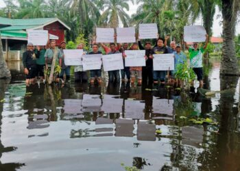 PENDUDUK mengadakan perhimpunan dalam banjir meminta pihak bertanggungjawab segera memperbaiki ban pecah di kampung mereka yang menjadi punca banjir di Kampung Permatang Pelandok di Pasir Salak, Perak.– UTUSAN/AIN SAFRE BIDIN