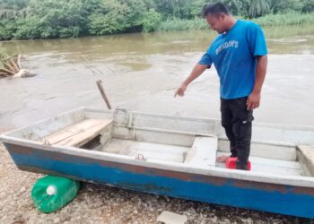 MUSTAPHA Kamal Nazry memeriksa botnya selepas kejadian diserang buaya di Sungai Kinta dekat Pasir Salak. - UTUSAN/AIN SAFRE BIDIN