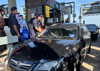 HAMZAH (kanan) menyampaikan cenderamata kepada pengguna jalan raya di Plaza Tol Sungai Dua, Butterworth, Pulau Pinang hari ini.-UTUSAN/SITI NUR MAS ERAH AMRAN