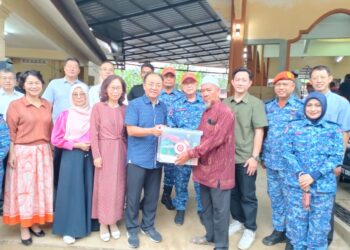 QUYANG Yujing (kiri) menyerahkan barang keperluan sebagai gimik bantuan kepada mangsa banjir di surau Pulau Gorek, Tumpat, Kelantan. - UTUSAN/ROHANA ISMAIL