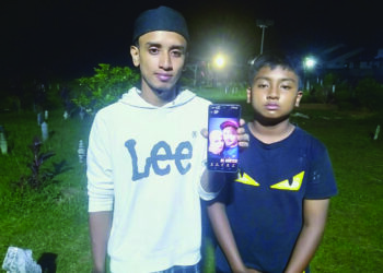 MOHD. Danial Ikmal bersama adiknya, Mohd. Danial Irfan menunjukkan gambar ibu bapa mereka yang maut nahas di Thailand selepas dikebumikan di Tanah Perkuburan Islam Masjid Darul ‘Ulum Merbau Pulas, Kulim.