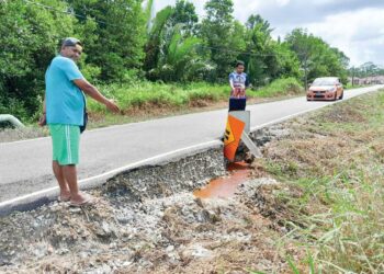 MD. AZHAR Tahir (kiri) dan Abdul Hakim Mohd. Ali menunjukkan jalan masuk yang mengalami kerosakan di Kampung Parit Makuasang, Benut, Pontian, Johor.