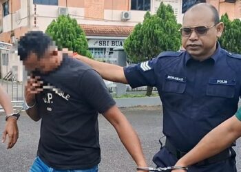 SUSPEK kelima (kiri) kes pukul lelaki orang kurang upaya (OKU) mental diiring keluar oleh anggota polis selepas mendapat perintah reman di Mahkamah Majistret Kemaman, Terengganu hari ini. - UTUSAN/NIK NUR IZZATUL HAZWANI NIK ADNAN