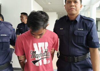 TERTUDUH diiringi anggota polis ketika dihadapkan ke Mahkamah Majistret, Ayer Keroh, Melaka.