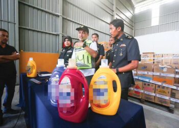 MUHAMMAD Nizam Jamaludin (tengah) menunjukkan cecair pencuci pakaian tiruan yang dirampas pada sidang akhbar di stor KPDN Kedah di Tunjang, Kubang Pasu, semalam.