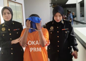 SUSPEK diiringi pegawai SPRM hadir di Mahkamah Majistret, Ayer Keroh, Melaka bagi mendapatkan perintah reman. - UTUSAN/MUHAMMAD SHAHIZAM TAZALI