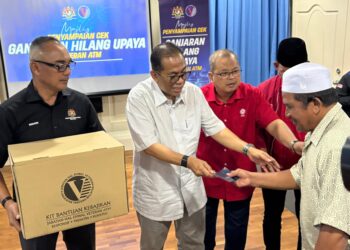 MOHAMED Khaled Nordin menyampaikan sumbangan kepada veteran ATM pada Majlis Penyampaian Ganjaran Hilang Upaya (GHU) dan kotak cakna Veteran ATM di Bangunan UMNO Bahagian Muar, Muar, hari ini.