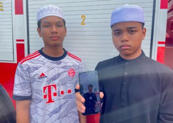 MOHAMAD Zawaata Afnan Mohamad Fuzi (kanan) di samping Muhammad Iqbal Mohd. Rodzi menunjukkan gambar Nur Haidhar Nasrul ketika ditemui di lokasi pencarian Sungai Padang Terap, Titi Chegar, Pendang.