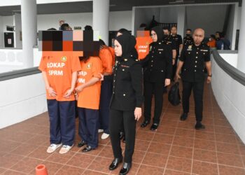 KESEMUA suspek diiringi pegawai SPRM ketika dibawa ke Mahkamah Majistret, Ayer Keroh, Melaka bagi mendapatkan perintah reman. - UTUSAN/MUHAMMAD SHAHIZAM TAZALI