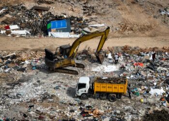 PEKERJA di tapak pelupusan sampah haram menggunakan jengkaut memunggah dan mengaut sisa dibawa oleh lori tong roll on roll off (roro) yang di kawasan berkenaan dekat Kampung Seri Sentosa, di Kuala Selangor, Selangor. - UTUSAN / Muhamad Iqbal Rosli