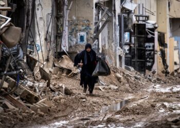 WANITA Palestin yang kehilangan tempat tinggal berjalan sambil membawa barangan peribadinya di kem pelarian Jenin di Tebing Barat yang diduduki, kelmarin.- AFP