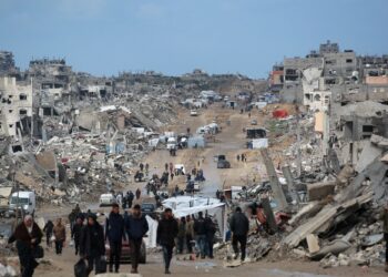 PENDUDUK Palestin berjalan melalui jalan kawasan berlumpur di tengah kemusnahan di Jabalia di utara Gaza.- AFP