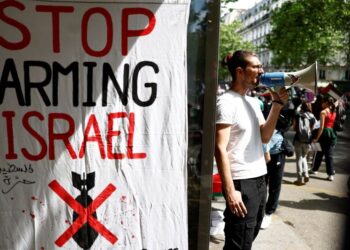 PENUNJUK perasaan memegang megafon di sebelah sepanduk bertulis 'Stop arming Israel', semasa demonstrasi menyokong rakyat Palestin di Paris, pada 8 Jun 2024.- AFP