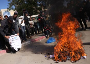 WARGA Palestin membakar baju seragam tahanan memaparkan logo perkhidmatan penjara dan Bintang Daud yang diberikan semasa pembebasan kelmarin, di Hospital Eropah di Khan Younis, selatan Gaza.- AFP