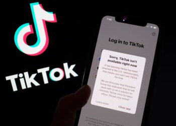 FOTO menunjukkan aplikasi TikTok pada skrin telefon pintar di hadapan logo aplikasi video popular milik China itu.- AFP