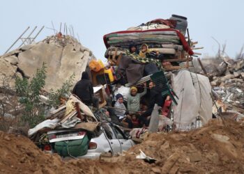 PENDUDUK Palestin membawa barangan mereka melalui kawasan runtuhan di jalan Salah al-Din di tengah Semenanjung Gaza.-AFP