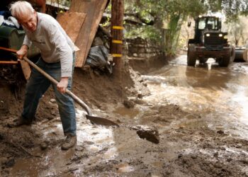 SEORANG penduduk membersihkan halaman rumahnya yang dilanda banjir lumpur di Sierra Madre, California.-AFP