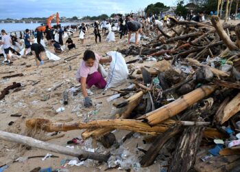 SUKARELAWAN mengutip sisa plastik dan sampah lain yang dihanyutkan ke kawasan pantai di Pulau Bali, Indonesia.-AFP