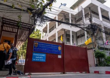 DUA pegawai polis memasuki pusat tahanan imigresen di Bangkok, yang menempatkan kumpulan etnik Uighur dari China.- AFP