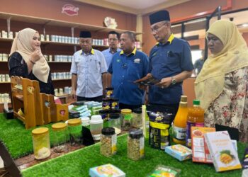 MOHD. Shukri Ramli (dua dari kanan) mendengar penerangan daripada Athifah Najwani Shahidan (kiri) berkaitan produk harumanis bersempena Majlis Pelancaran Produk: Kuih Raya Edisi Harumanis di Pusat Agro Pelancongan Bukit Temiang, Padang Besar, Perlis hari ini. -UTUSAN/ASYRAF MUHAMMAD