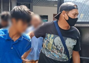 BOMOH muda (kiri) diiring polis keluar dari Mahkamah Sesyen Kemaman, Terengganu selepas mendapat perintah sambung reman. -UTUSAN/NIK NUR IZZATUL HAZWANI NIK ADNAN