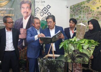 JOHARI Abdul Ghani meneliti buku Agarwood: Diamond of The Forest yang dilancarkan di Restoran Hening, Jalan Damai, Kuala Lumpur. – UTUSAN/MUHAMAD IQBAL ROSLI