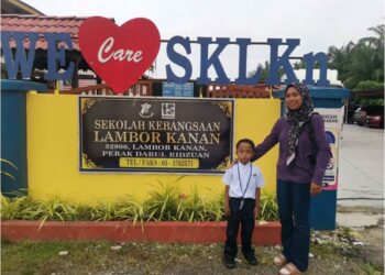 NOOR Athirah Che Man menghantar anaknya, Muhamad Ziyaan Mohamad Zaidi memulakan persekolahan di SK Lambor Kanan di Perak Tengah, semalam. 
– UTUSAN/AIN SAFRE BIDIN