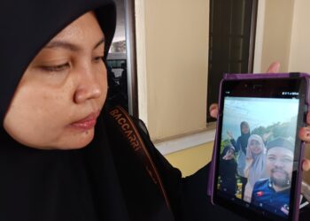 NURFATIN Farhanah Shapie menunjukkan gambarnya dan adik beradik lain bersama Mohd. Najmuddin ketika ditemui pemberita di Unit Forensik Hospital Jempol hari ini.