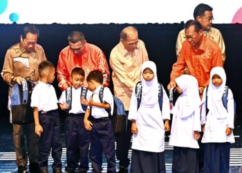 WAN ROSDY Wan Ismail (tiga dari kiri) menyantuni murid sekolah yang menerima sumbangan beg dan baju sekolah pada program Konvensyen Muafakat Felda Pahang di Dewan Auditorium RTM di Kuantan, Pahang. - FOTO/SHAIKH AHMAD RAZIF