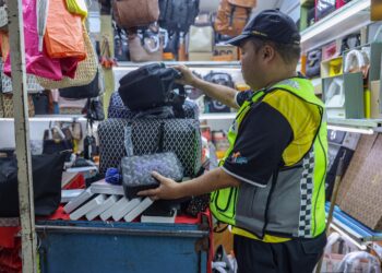 ANGGOTA KPDN memeriksa barangan tiruan ketika Op Putra di Jalan Petaling, Kuala Lumpur.