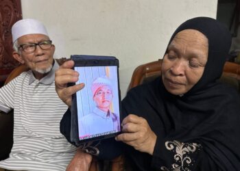 RUHANI Hussin menunjukkan gambar kenangan arwah anaknya di rumahnya di Kampung Bayu Lalang, Pasir Mas, Kelantan. – UTUSAN/ROHANA MOHD.NAWI