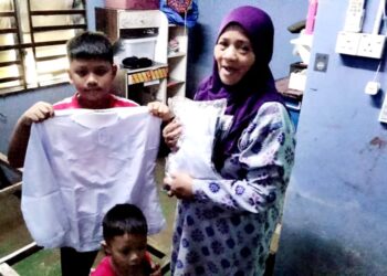 MANJA Mohd. Noar menunjukkan baju sekolah cucunya yang sempat diselamatkan apabila kediaman mereka di Kampung Baru Sungai Mas, Kota Tinggi , Johor dilanda banjir kelmarin.