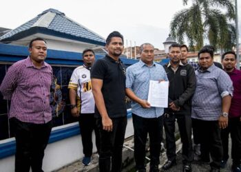 NAZIRUL Jamaluddin (tengah) menunjukkan laporan polis yang dibuat di Balai Polis Pekan Baru, Ipoh hari ini. - UTUSAN