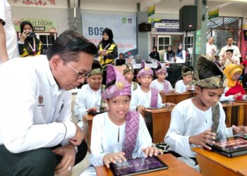 AZMAN Adnan (kiri) memerhatikan Muhammad Ariq Anaqi Mohd. Taufiq bermain alat muzik hanya menggunakan tablet pada Majlis Peluncuran Sekolah Digital di SK Seri Telok di Parit Yaani, Batu Pahat, Johor.