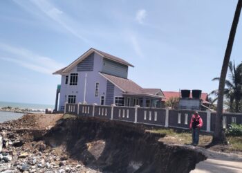 MOHD. Yazit Idris menunjukkan tanah bahagian pagar rumahnya yang runtuh akibat ombak besar di Kampung Tanjung Batu Rakit, Terengganu. -  UTUSAN/KAMALIZA KAMARUDDIN