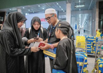 AHMAD Nor Al Faizan Jusoh bersama  dua anaknya memeriksa pasport sebelum berlepas ke Tanah Suci di Lapangan Terbang Antarabangsa Kuala Lumpur, semalam. – UTUSAN/FAIZ ALIF ZUBIR