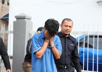 TERTUDUH diiring polis selepas dihadapkan di Mahkamah Sesyen, Kemaman, Terengganu atas pertuduhan melakukan amang seksual fizikal terhadap seorang kanak-kanak perempuan. - UTUSAN/NIK NUR IZZATUL HAZWANI NIK ADNAN