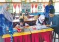 ZAITON Hashim (kiri) dan Ismail  Daud (kanan) bersama murid pada hari pertama sesi persekolahan 2024/2025 di SK Tebing Rebak di Bagan Datuk semalam. – UTUSAN/AIN SAFRE BIDIN