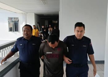 TERTUDUH diiringi anggota polis ketika dihadapkan ke Mahkamah Sesyen Ayer Keroh, Melaka.