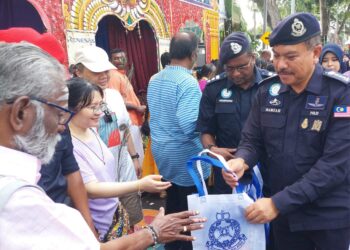 HAMZAH Ahmad (kanan) mengagihkan cenderamata kepada pengunjung yang hadir pada sambutan Thaipusam di Jalan Brown, Kebun Bunga, George Town, Pulau Pinang hari ini.