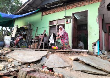 ASMAH Ibrahim menyapu halaman rumahnya yang terjejas di Kampung Jubakar Pantai, Tumpat, Kelantan selepas dilanda banjir pada hujung November 2024.