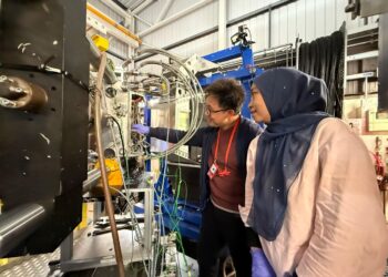 RAFIZA Abdul Razak bersama pelajar, Dickson Ling sedang menyediakan sampel untuk pengujian Engin-X di Rutherford Appleton Laboratory, United Kingdom (UK) baru-baru ini.-UTUSAN