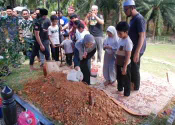 ANAK perempuan Allahyarham Roslan Salleh menyiram air ke atas kubur di Tanah Perkuburan Islam Kampung Rantau Panjang, Masjid Tanah, Melaka. - UTUSAN/AMRAN MULUP