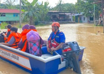 ANGGOTA Angkatan Pertahanan Awam (APM) membantu memindahkan mangsa banjir yang terjejas di Membakut semalam. - IHSAN APM