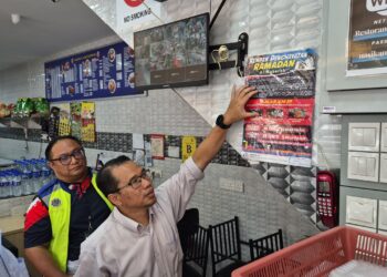 MD. AZHAN Samat (kanan) menampal poster Kempen Penghayatan Ramadan JAIM di sebuah premis di Bukit Baru, Melaka. - UTUSAN/ MUHAMMAD SHAHIZAM TAZALI