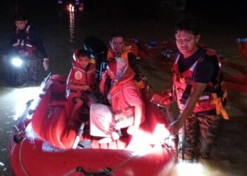 ANGGOTA bomba memindahkan mangsa banjir di Kampung Laut, Skudai, malam tadi.