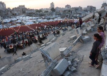 PENDUDUK Palestin berkumpul di celah runtuhan bangunan untuk jamuan iftar di Gaza City. – AFP